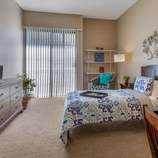 A cozy bedroom with a single bed, wooden furniture, and soft lighting.