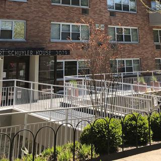 Entrance to a brick apartment building with railings and plants.