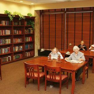 People reading at tables inside a library.