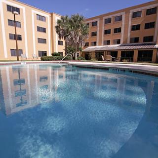 A hotel with a large outdoor swimming pool reflecting the building.