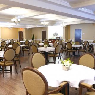 A neatly arranged dining area with round tables and upholstered chairs, ready for guests.