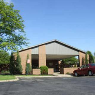 A brick building with a parking lot and cars under a clear blue sky.