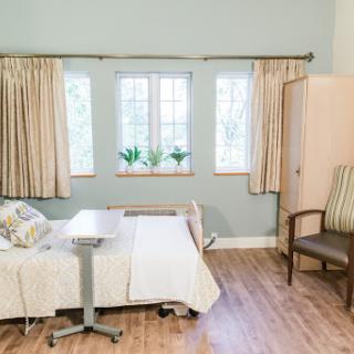 A well-lit hospital room featuring a patient bed, comfortable seating, and decorative plants.