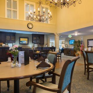 A spacious dining area with elegant chandeliers, tables, and chairs.