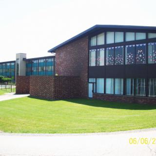 A modern brick building with large windows and a well-maintained lawn under a clear sky.