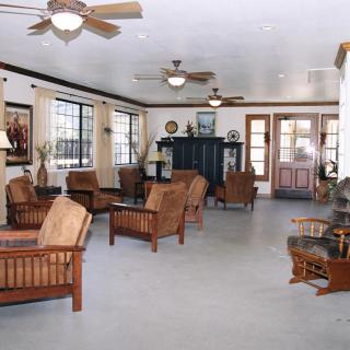 A spacious living room with wooden furniture and ample natural light streaming through large windows.