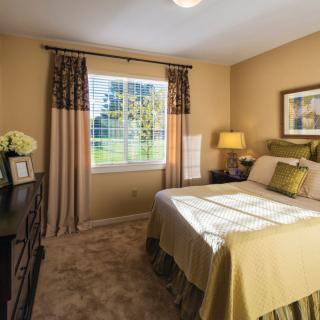 A cozy bedroom with a neatly made bed, soft lighting, and a view of the outdoors through the window.