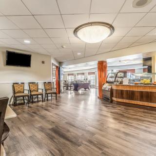 A spacious lobby featuring wood flooring, comfortable seating, and a large chandelier.