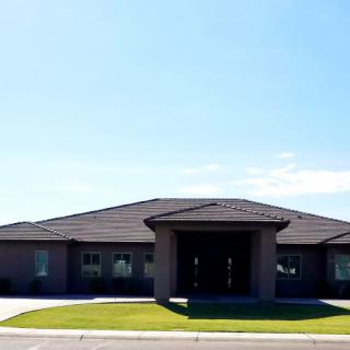 A suburban house with a well-maintained lawn under a clear blue sky.