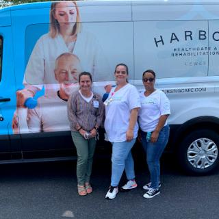 Three individuals posing in front of a branded healthcare van.