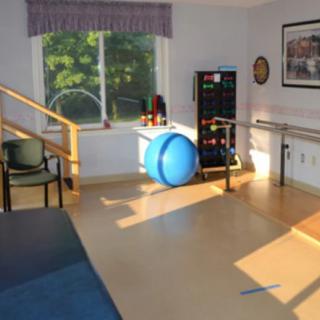 A physical therapy room with exercise equipment and parallel bars for rehabilitation exercises.