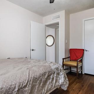 A minimalist bedroom with a bed, chair, and white walls.