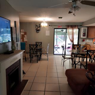 A cozy living space with a connected dining area and kitchen, featuring a television, fireplace, and ceiling fan.