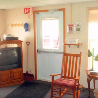 A cozy living room with a television, rocking chair, and an exit door.