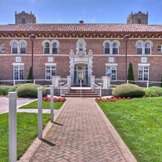 A historic brick building with a central entrance and well-maintained landscaping.