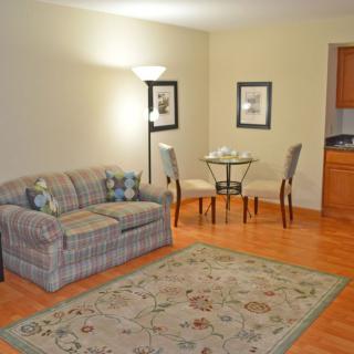 A cozy living room with a sofa, small dining area, and a lamp for lighting.