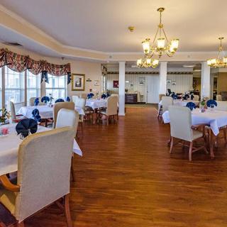 An elegant and spacious dining room with neatly arranged tables and chairs, adorned with chandeliers.