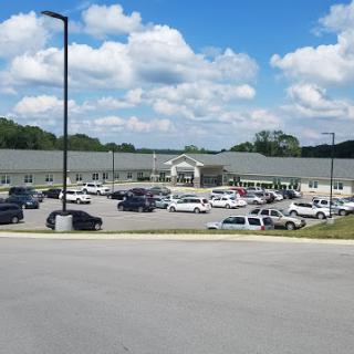 A view of a commercial building surrounded by a parking lot filled with vehicles under a partly cloudy sky.