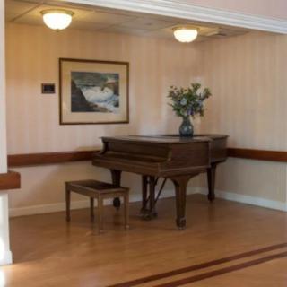 A cozy corner featuring a grand piano, artwork, and floral arrangement.