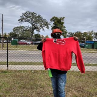 A person showcasing a red hoodie against an outdoor background.