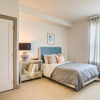 A cozy and modern bedroom with a neatly made bed, nightstand, and lamp.