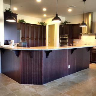 A modern kitchen with dark cabinets and pendant lighting over a large island.