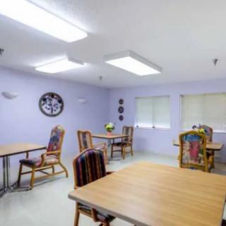 A simple dining room setup with wooden tables and colorful cushioned chairs.