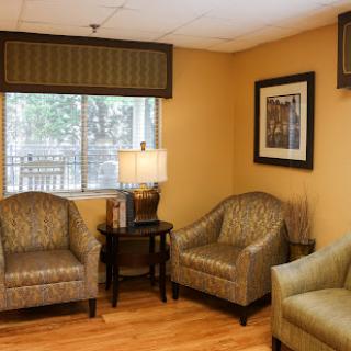 A cozy living room setup featuring comfortable chairs, a lamp, and an artwork on the wall.