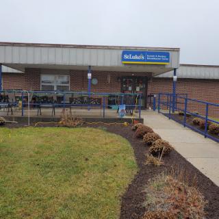A view of the building's entrance with landscaped surroundings and cloudy weather.