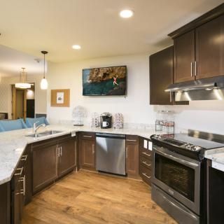 A modern kitchen interior with stainless steel appliances and wooden cabinetry.