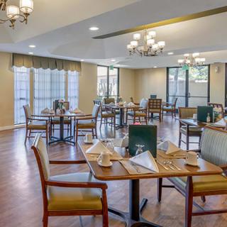 An elegant dining room setup with neatly arranged tables and chairs, illuminated by chandeliers.