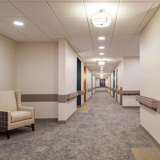 A well-lit, modern hallway with a comfortable chair placed against the wall.