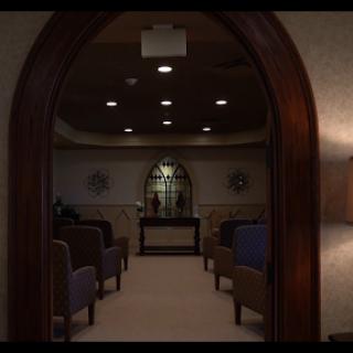 A serene waiting room viewed through an arched doorway, featuring rows of chairs and soft lighting.