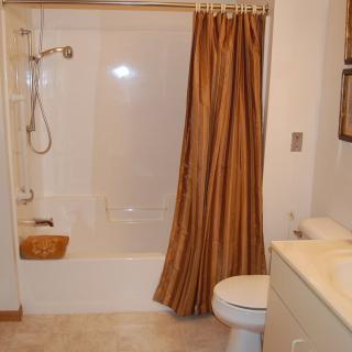 A clean and tidy bathroom with a bathtub, shower curtain, toilet, and sink.