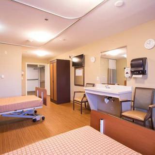 A well-organized hospital room with two beds, a sink, and chairs, designed for patient care.