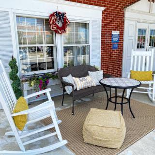 A cozy outdoor seating area featuring rocking chairs, a small table, and decorative accents.