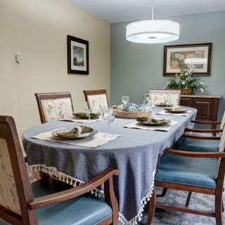 A well-appointed dining room with a table set for a meal, featuring elegant chairs and soft lighting.