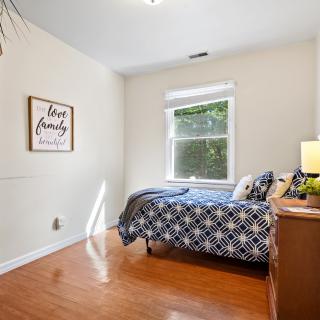 A cozy bedroom with a single bed, wooden flooring, and a window allowing natural light.