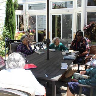 A group of elderly people sitting and socializing on a patio.