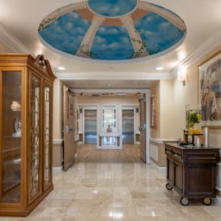 An elegantly designed hallway featuring a beautifully painted ceiling and stylish furnishings.