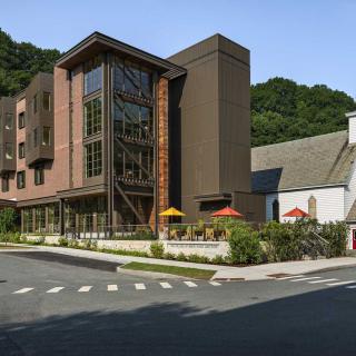 A modern building with outdoor seating and lush greenery in an urban setting.