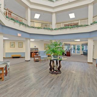 A spacious and well-lit atrium lobby featuring elegant furniture and a central plant display.
