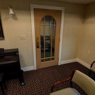 A cozy room with a patterned carpet, wooden door, and seating area.