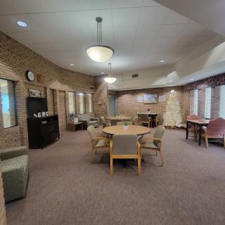 A spacious community room featuring round tables and comfortable seating, designed for social gatherings.