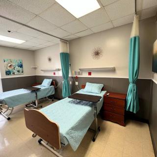 A clean and organized hospital room with two beds separated by curtains.