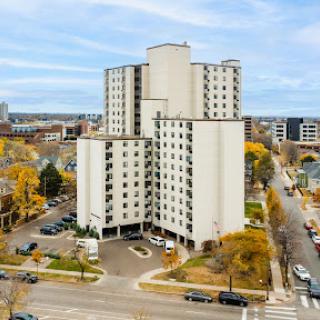 Aerial view of a modern residential high-rise building surrounded by urban infrastructure and autumn foliage.