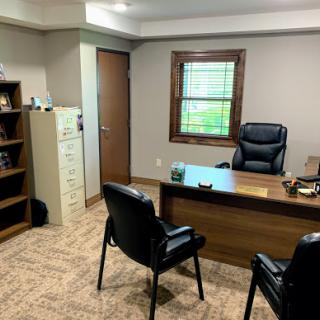 A modern office space featuring a wooden desk, comfortable chairs, and organized shelving.