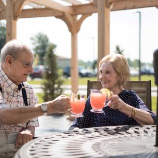 An elderly couple enjoying a refreshing drink outdoors on a sunny day.