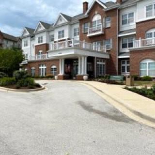 A multi-story residential building with a driveway and landscaped surroundings.