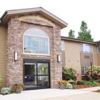 A two-story building with a stone facade and landscaped entrance.